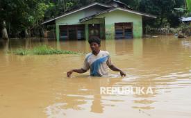 Warga melintasi banjir di Desa Napai, Woyla Barat, Aceh Barat, Aceh, Jumat (28/11/2025). Data Pusdalops BPBD Aceh Barat mencatat bencana banjir yang disebabkan tingginya intensitas hujan dan meluapnya sungai krueng Woyla dan sungai Meureubo terus meluas dari 58 desa terendam menjadi 64 desa yang tersebar di 10 Kecamatan dengan rincian 3.725 kepala keluarga atau 7.418 terdampak. 