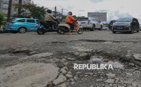 Pengendara melintasi jalan berlubang di Jalan Tanjung Duren, Jakarta Barat, Senin (2/2/2026). Menurut warga setempat, kondisi jalan rusak tersebut disebabkan oleh intensitas hujan yang tinggi. SementaraPemerintah Provinsi DKI Jakarta mengaku telah memperbaiki sebanyak 6.000 titik jalan berlubang dan akan terus melakukan perbaikan secara berkala.