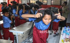 Sejumlah siswa melindungi kepalanya dengan ransel saat mengikuti simulasi mitigasi bencana gempa di SDN Kedaung Wetan 2, Kota Tangerang, Banten, Selasa (15/10/2024). Anggota Taruna Siaga Bencana (Tagana) Kota Tangerang memberikan pengetahuan mitigasi bencana di lingkungan sekolah guna memperkuat kesiapsiagaan pelajar dalam menghadapi bencana. 