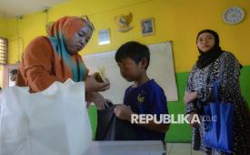 Wali murid membagikan paket Makan Bergizi Gratis (MBG) kepada siswa di SDN Pabuaran Tumpeng 2, Kota Tangerang, Banten, Rabu (24/12/2025). Penyaluran paket MBG berupa roti, buah-buahan, susu, keju dan telur yang dilakukan setiap seminggu sekali tersebut guna memastikan pemenuhan gizi peserta didik tetap terjaga selama masa libur sekolah. 