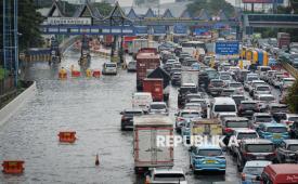 Petugas memasang pembatas jalan di gerbang tol yang terendam banjir di Jalan Tol Sedyatmo, Cengkareng, Jakarta, Senin (12/1/2026). Jalan tol yang merupakan akses menuju Bandara Soekarno-Hatta tersebut terendam banjir setinggi 15-50 sentimeter akibat tingginya intensitas hujan. 