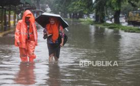 Petugas BPBD menuntun warga berjalan melewati banjir di Jalan Letjen Suprapto, Cempaka Putih, Jakarta, Kamis (29/2/2024). Banjir di sejumlah ruas jalan dilaporkan masih terjadi hingga hari ini. 
