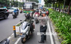 Polisi menertibkan pengendara motor yang melintas di jalur sepeda Jalan Jenderal Sudirman, Jakarta, Senin (28/4/2025).