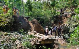 Sejumlah warga bergotong royong menyingkirkan material jembatan yang ambrol di Plosogaden, Candiroto, Temanggung, Jawa Tengah, Senin (18/5/2026). Jembatan ambrol akibat hujan deras yang menyebabkan pondasi jembatan tergerus derasnya aliran sungai.