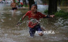 Anak bermain saat banjir yang menggenangi jalan di kawasan Cempaka Putih, Jakarta, Ahad (18/1/2026). Banjir setinggi sekitar 40-60 centimeter tersebut terjadi sejak pagi pukul 07.00 WIB yang disebabkan oleh intensitas hujan yang tinggi serta luapan air dari kali dan aliran drainase kawasan tersebut.