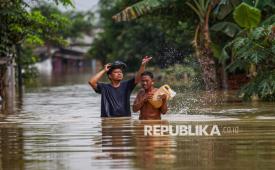 Dua warga melintasi jalan yang terendam banjir di Desa Karangligar, Telukjambe, Karawang, Jawa Barat, Senin (19/1/2026). 