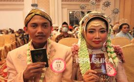 Sepasang pengantin menunjukkan buku nikahnya saat nikah massal di Surabaya, Jawa Timur, Selasa (30/8/2022). Pemkot Surabaya menikahkan secara massal 120 pasangan pengantin dari berbagai golongan umur. 