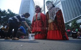   Seorang warga memasukkan uang untuk ondel-ondel setelah berfoto bersama pada saat Car Free Day (CFD) kawasan Thamrin, Jakarta Pusat.