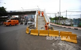 Petugas PPSU membersihkan sampah di Jembatan Penyeberangan Orang (JPO) di kawasan Jalan Dewi Sartika, Jakarta.
