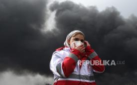 Seorang anggota Bulan Sabit Merah Iran berjalan ketika asap masih mengepul dari Kilang Minyak Shahran menyusul serangan udara tadi malam di Teheran, Iran, 8 Maret 2026.