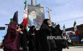 Wanita Iran berjalan di dekat poster mendiang pemimpin tertinggi Iran Ayatollah Ali Khamnei saat menghadiri pemakaman korban serangan Israel dan AS, di pemakaman Behesht Zahra di selatan Teheran, Iran, 26 Maret 2026.