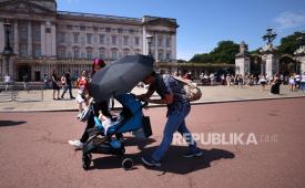 Sebuah keluarga melindungi anak mereka dari terik matahari di luar Istana Buckingham saat cuaca panas di London, Inggris, 26 Juni 2026. Peringatan merah dari Met Office tentang panas ekstrem masih berlaku untuk wilayah Timur dan Tenggara Inggris, karena gelombang panas terus melanda sebagian besar wilayah Inggris.