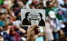 Seorang pengunjuk rasa memegang poster yang menampilkan Perdana Menteri India Narendra Modi (tengah) saat ia dicium oleh pengusaha India Mukesh Dhirubhai Ambani (kiri) dan miliarder India sekaligus Chairman Adani Group, Gautam Adani (kanan), dalam sebuah aksi unjuk rasa di Bangalore, India, pada 25 Juli 2026.