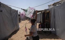 Seorang anak laki-laki Palestina menerbangkan layang-layang di antara tenda-tenda di kamp al-Mawasi, dekat Khan Younis, Jalur Gaza bagian selatan, pada 27 Agustus 2026.