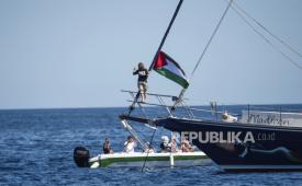 Aktivis iklim Greta Thunberg berdiri di dekat bendera Palestina setelah menaiki kapal Madleen dan sebelum berlayar ke Gaza bersama dengan aktivis Koalisi Armada Kebebasan, berangkat dari pelabuhan Sisilia Catania, Italia, Minggu, 1 Juni 2025.