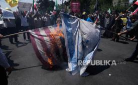 Demonstran membakar bendera Israel dan Amerika Serikat saat menggelar aksi unjuk rasa di Teheran, Iran, Jumat (20/6/2025).