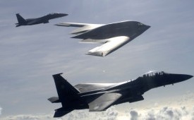 Dua jet tempur F-15 E Eagle bersama pesawat pengebom B-2 dalam formasi udara.