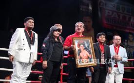 Gubernur Maluku Hendrik Lewerissa berpose dengan lukisan Ellyas Pical yang dibelinya dalam lelang rangkaian acara Kejuaraan Tinju Amatir dan Profesional Pattimura International Big Fight 2026 di Studio TVRI Senayan, Jakarta, Jumat (29/5/2026) malam.