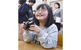 Seorang siswa di Sekolah Tunanetra Metropolitan Hachioji Tokyo memegang kamera yang dirancang untuk penyandang disabilitas penglihatan. 