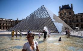Warga Paris dan wisatawan bersantai di air mancur Piramida Museum Louvre di Paris, Prancis, 19 Juli 2022. Lebih dari 100 Penyidik diturunkan untuk meinvestigasi pencurian di Museum Louvre.