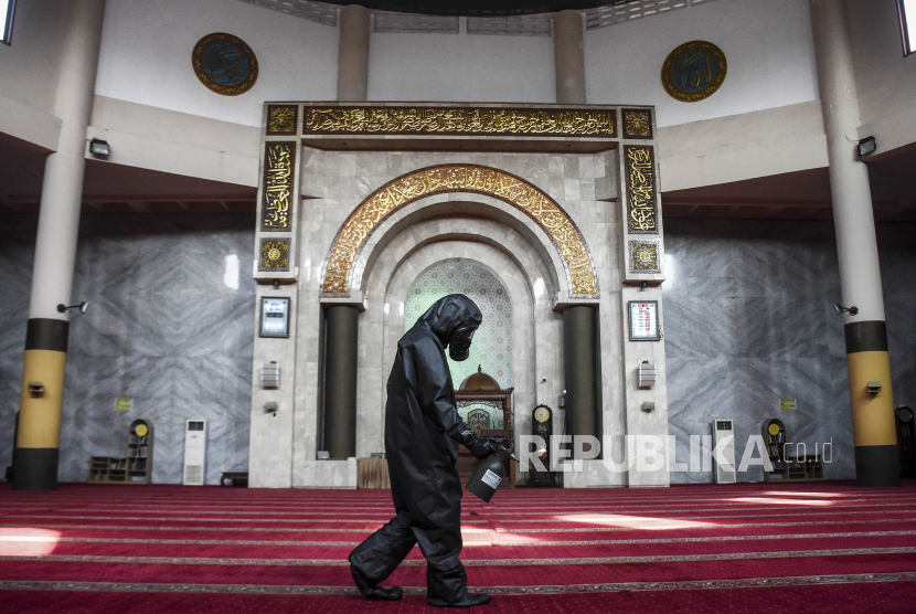 Personel polisi menyemprotkan cairan disinfektan di sajadah Masjid Raya Bandung, Jalan Dalem Kaum, Kota Bandung. (Abdan Syakura/Republika)