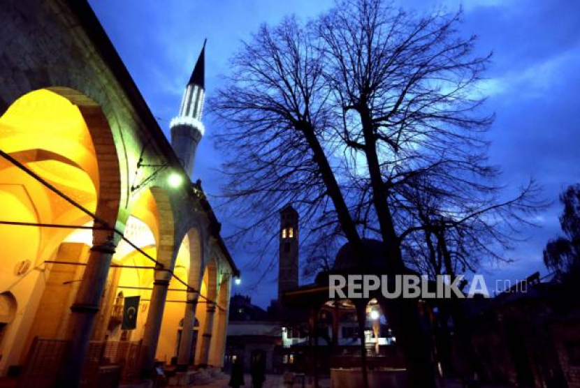 Pemandangan umum menunjukkan menara Masjid Gazi Husrev-beg (kiri) dan menara jam (kanan) saat malam Ramadhan di Sarajevo, Bosnia dan Herzegovina, Senin (10/4/2023). Bacaan Niat dan Doa Sholat Tahajud serta Keistimewaannya. Foto: EPA-EFE/FEHIM DEMIR