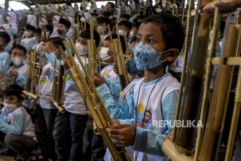 Anak anak memainkan angklung.