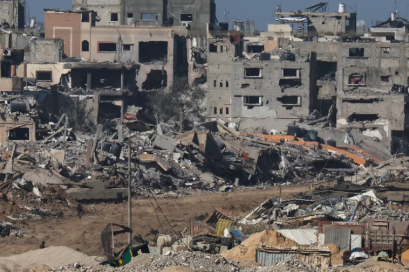 Gambar yang diambil dari Israel selatan pada 22 Desember 2023, menunjukkan tank tentara Israel berguling melewati puing-puing bangunan di Gaza [Jack Guez/AFP]