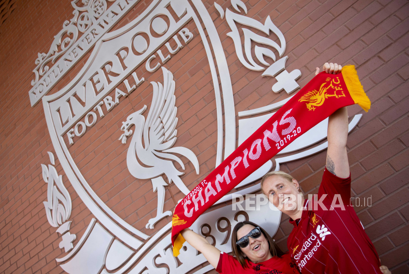 Penggemar berpose di depan lambang Liverpool di luar Stadion Anfield. Foto: EPA-EFE/PETER POWELL