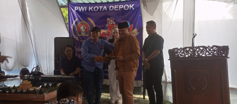 Ketua PWI Kota Depok, Rusdi Nurdiansyah menyerahkan tumpeng kepada tokoh masyarakat Kota Depok, H. Yahman pada acara Peringatan Hari Pers Nasional, Jumat (9/2) di halaman kantor PWI Depok.