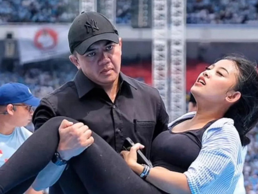 Foto yang viral di medos di mana Mayor Teddy terlihat menggendong seorang wanita yang mau pingsan di tengah kampanye akbar terakhir Prabowo-Gibran di GBK pada Sabtu (10/2/22024). Wanita tersebut memberikan klarifikasi setelah dituduh pura-pura pingsan. (Dok. Istimewa)