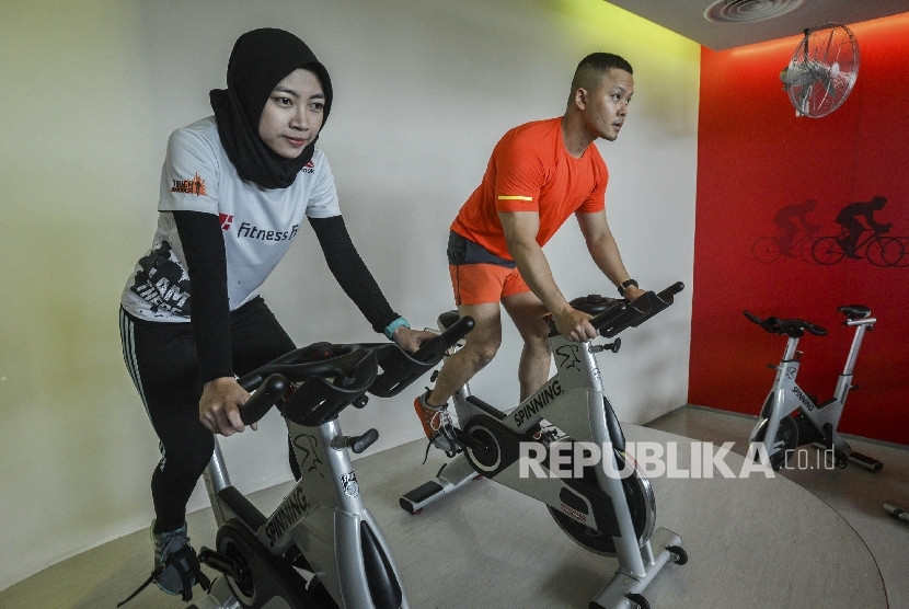 Wanita dan pria berolahraga sepeda statis-Republika/Raisan Al Farisi