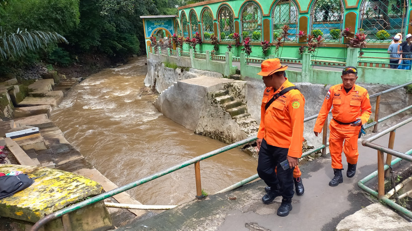 Petugas Basarnas Bandung memantau titik lokasi tiga orang santri yang hanyut terbawa arus di Sungai Cikapundung. Dok Republika