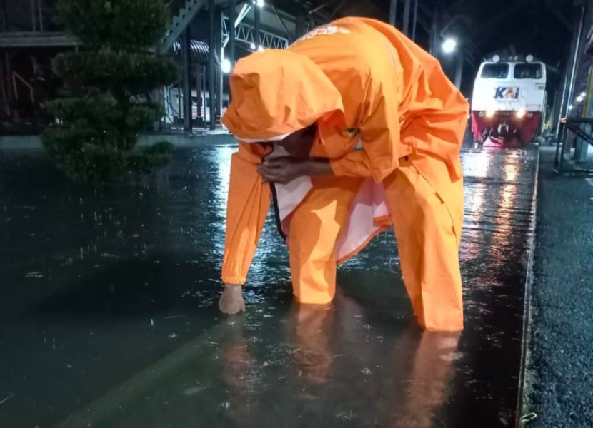 Seorang petugas PT KAI sedang melakukan pengecekan kedalaman banjir. Banjir di Semarang akibatkan Kereta Api Pandalungan terlambat datang di stasiun Jember (Foto: Dok.Daop 9 Jember) 