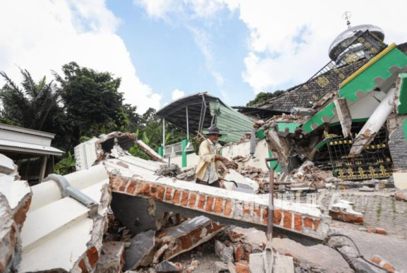 Warga melintas di dekat Masjid Jamik Al Muhajirin yang sebangian bangunannya roboh akibat gempa di Dusun Balikbakgunung, Sangkapura, Pulau Bawean, Gresik, Jawa Timur, Ahad (24/3/2024). (ANTARA FOTO/Rizal Hanafi)