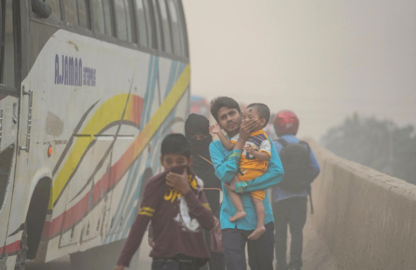 Sebuah keluarga di Dhaka, Bangladesh, berjalan melewati polusi udara./Foto: Zabed Hasnain Chowdhury/Shutterstock