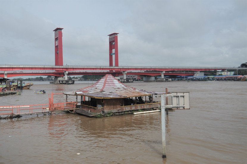 Rumah rakit di atas Sungai Musi dengan latar belakang Jembatan Ampera, Palembang. (Foto: SumatraLink.id/Mursalin Yasland)