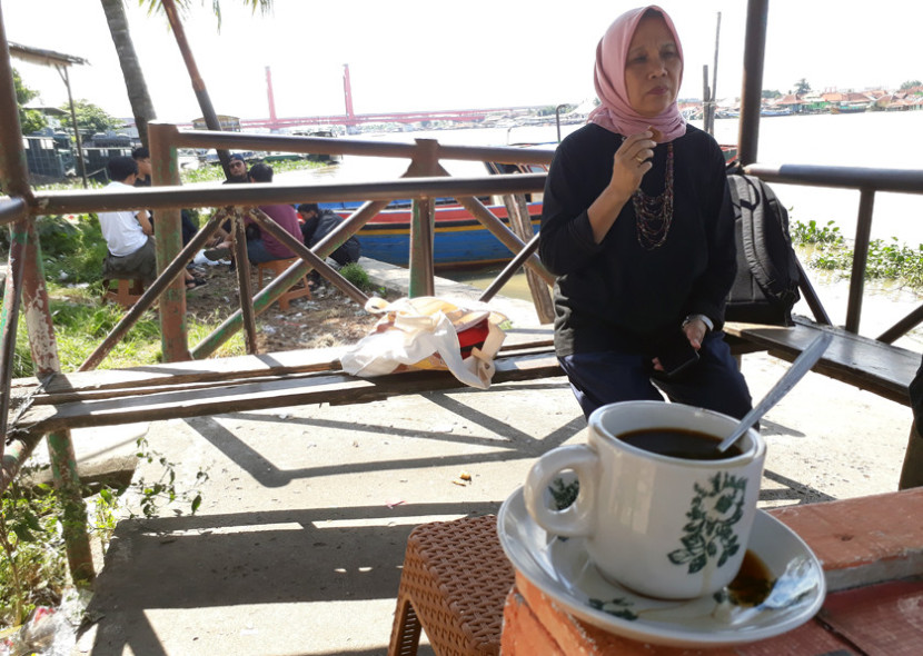 Menikmati kopi di warung kopi Sekanak yang ada di tepi sungai Musi berteman pemandangan Jembatan Ampera. (FOTO: Maspril Aries)