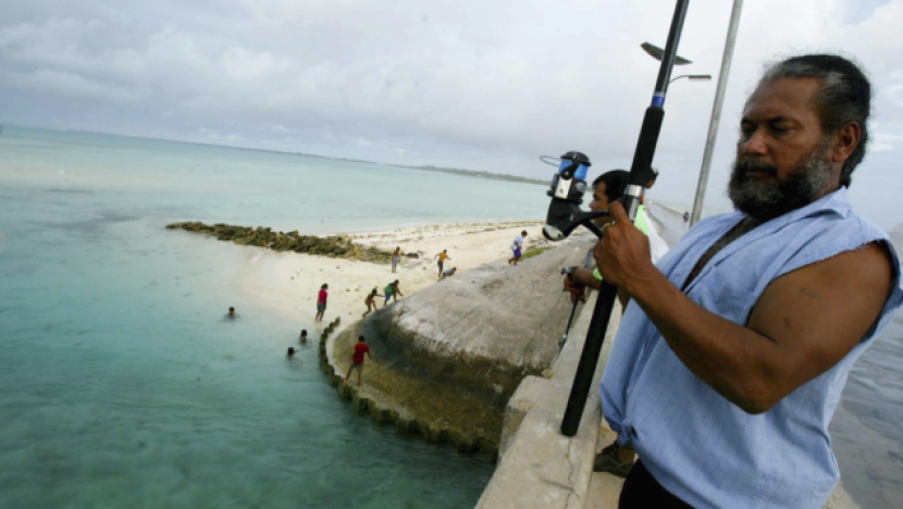 Seorang warga memancing di jembatan yang ada di Tarawa atol, Kiribatu, beberapa waktu lalu. (Foto: Richard Vogel/AP)