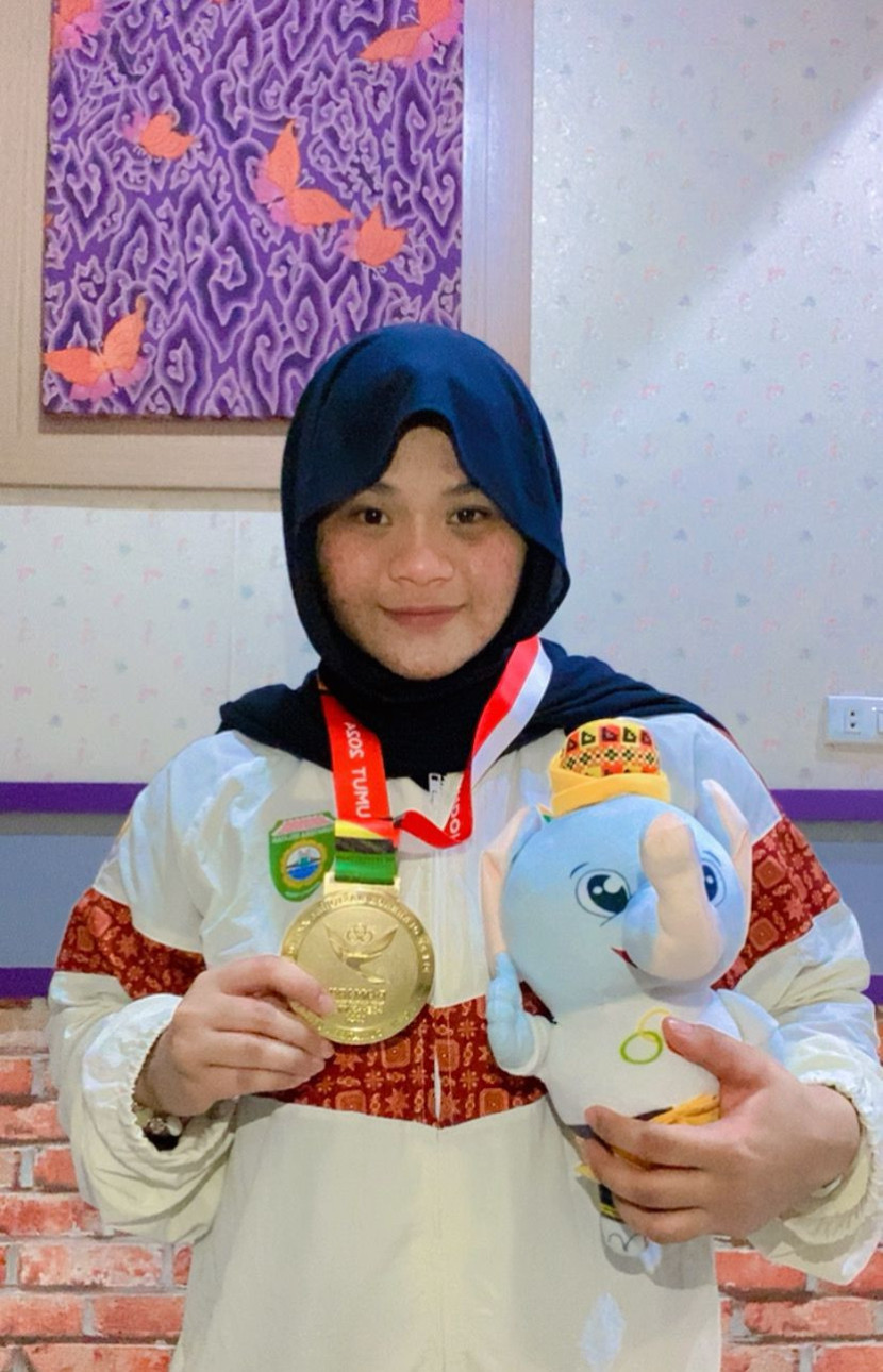 Lifter Indah Afriza dengan medali emas dan boneka maskot PON Aceh - Sumut 2024. (FOTO: Dinas Kominfo Muba)