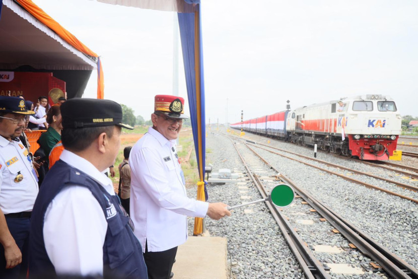 Sekretaris Daerah Sumsel Edward Candra mengenakan topi berwarna merah menjadi PPKA (Pengatur Perjalanan Kereta Api) melepas rangkaian kereta barang pengangkut batu bara dipasang bendera merah putih. (FOTO: Humas Pemprov Sumsel)