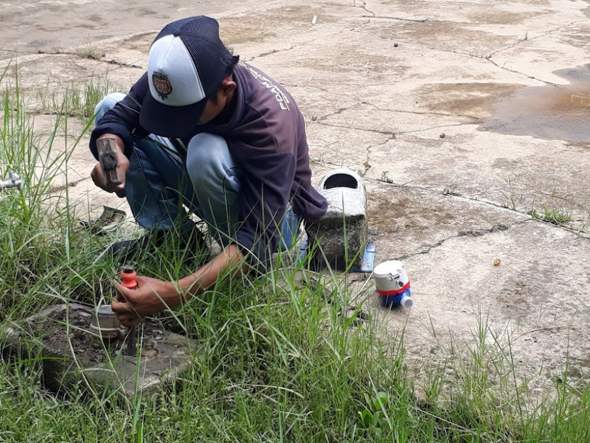 ekerja PDAM Tirta Musi tengah mengganti meteran air. (FOTO: Maspril Aries)