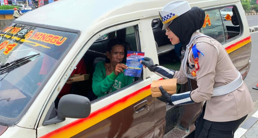 Kanit Keamanan dan Keselamatan Lalulintas (Kamsel) Polrestro Depok, AKP Elly Padiansari membagikan makanan dan brosur tertib berlalulintas ke pengemudi angkot dalam giat Jumat Berkah, Jumat (18/01/2024). (Foto: Dok Ruzka Indonesia)