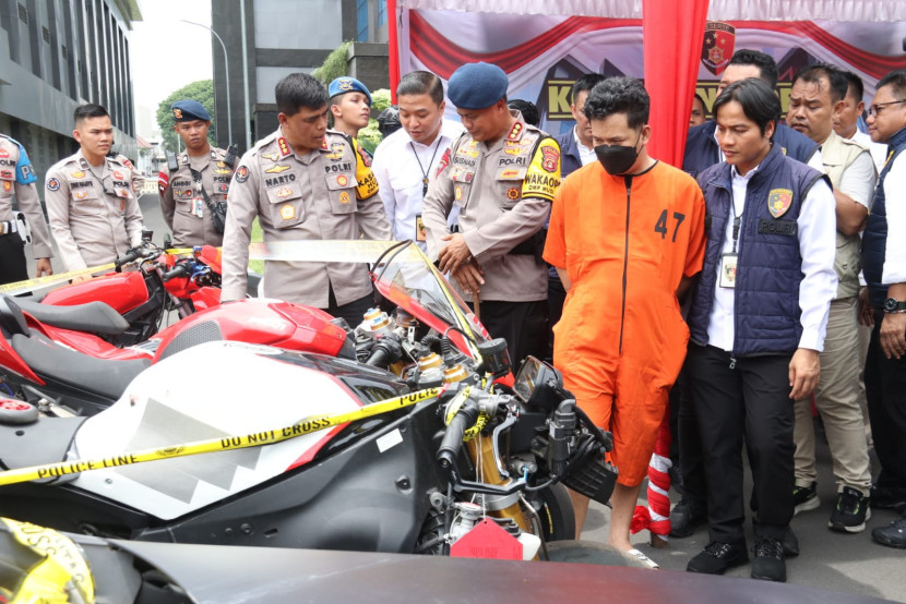 Tersangka (berbaju oranye) dan barang bukti motor yang disita di Polda Sumsel. (FOTO: Humas Polda Sumsel)