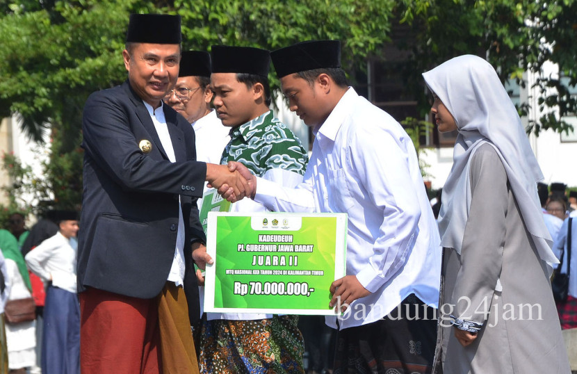 Pj Gubernur Jabar Bey Machmudin memberikan kadeudeuh kepada para santri berprestasi saat peringatan Hari Santri Nasional, di Gedung Sate Bandung, Kota Bandung, Selasa (21/10/2024). Foto: Edi Yusuf