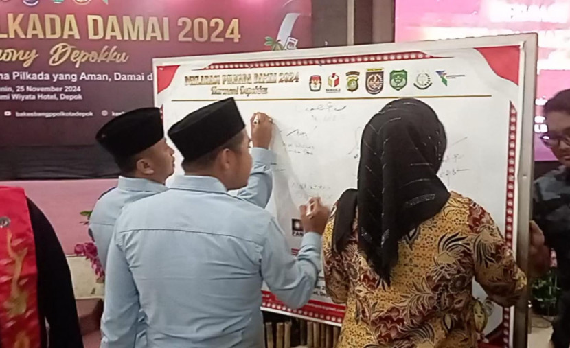 Pasangan calon Supian Suri dan Chandra Rahmansyah (No. 2) bersama dengan pasangan No. 1 Ririn Farabi menandatangani komitmen Pilkada Depok Damai, Senin (25/11).