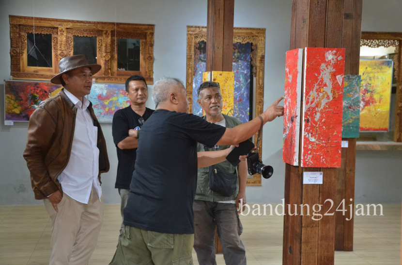 Dede Comex (bertopi) bersama seniman Andi Sopiandi berdiskusi saat pameran lukisan 'Titik Hening, Ekspresi Dikala Sepi' karya Dede Comex, di Galeri Lorong Senja, Cijagra, Kota Bandung, Senin (24/11/2024). Foto: Edi Yusuf