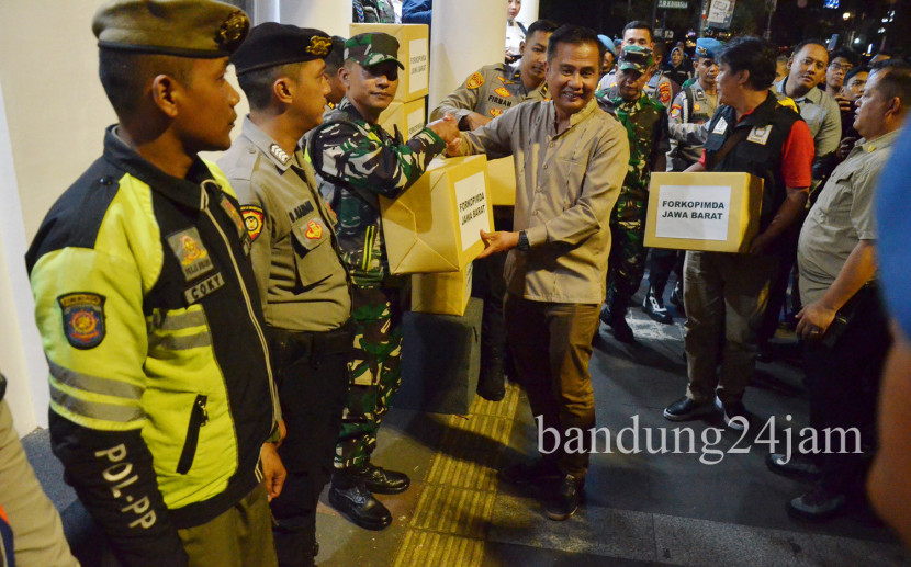 Pj Gubernur Jabar Bey Machmudin menyerahkan bingkisan kepada petugas gabungan saat meninjau malam Tahun Baru 2025 di kawasan Cikapayang, Kota Bandung, Selasa (31/12/2024). Foto: Edi Yusuf