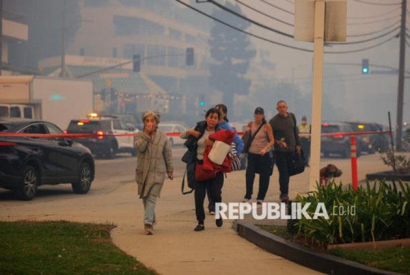 Warga berjalan untuk di evakuasi saat terjadi kebakaran besar yang melanda kawasan Pacific Palisades, Los Angeles, Kalifornia, Selasa (7/1/2025). Foto: REUTERS/Mike Blake