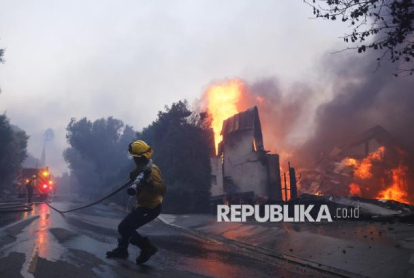 Petugas pemadam kebakaran berusaha memadamkan kebakaran besar yang melanda kawasan Pacific Palisades, Los Angeles, Kalifornia, Selasa (7/1/2025). Foto: AP Photo/Etienne Laurent